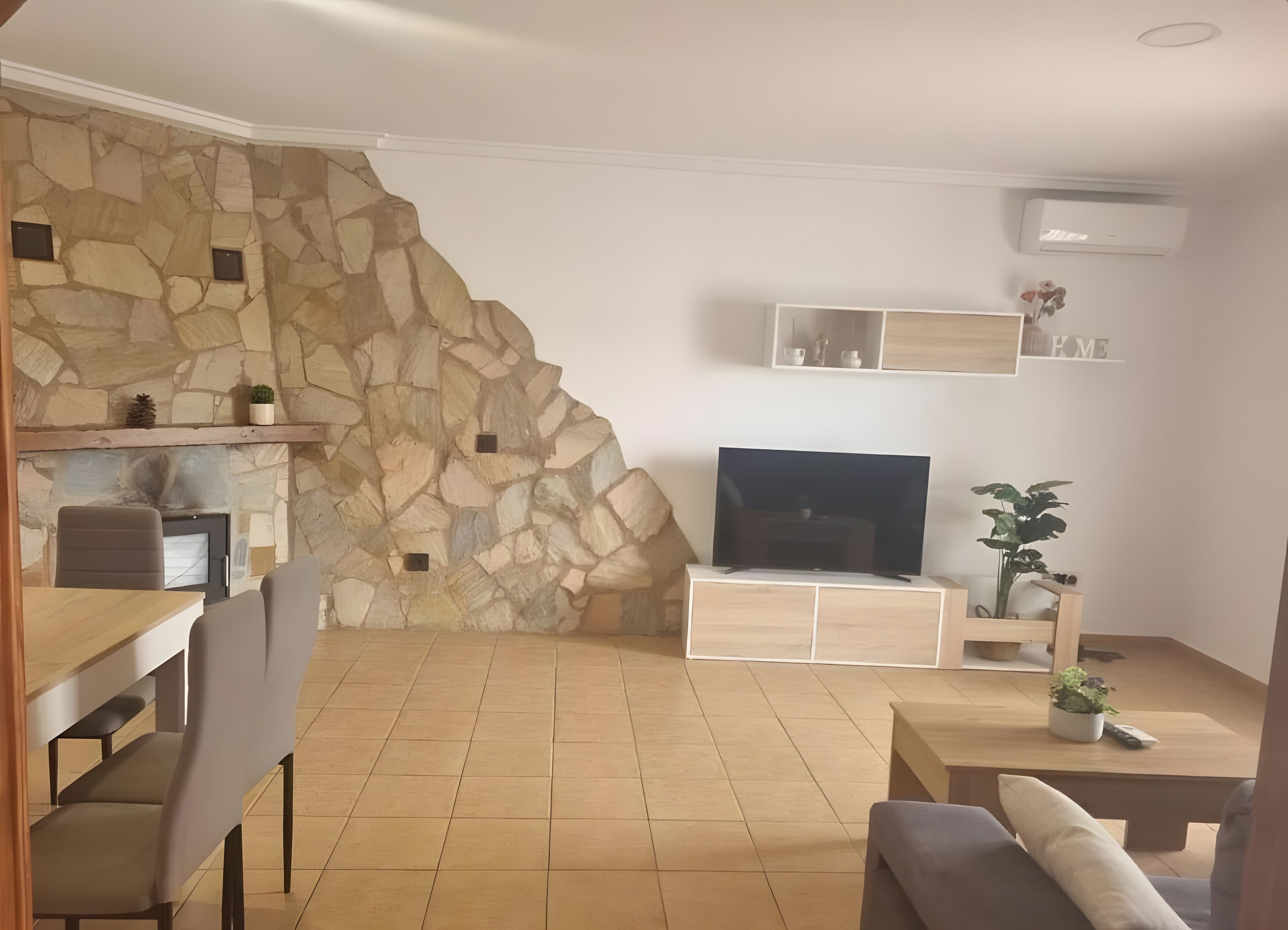 Ein Wohnzimmer mit Steinsäule, Flachbildfernseher, Couchtisch aus Holz und einer Couch.