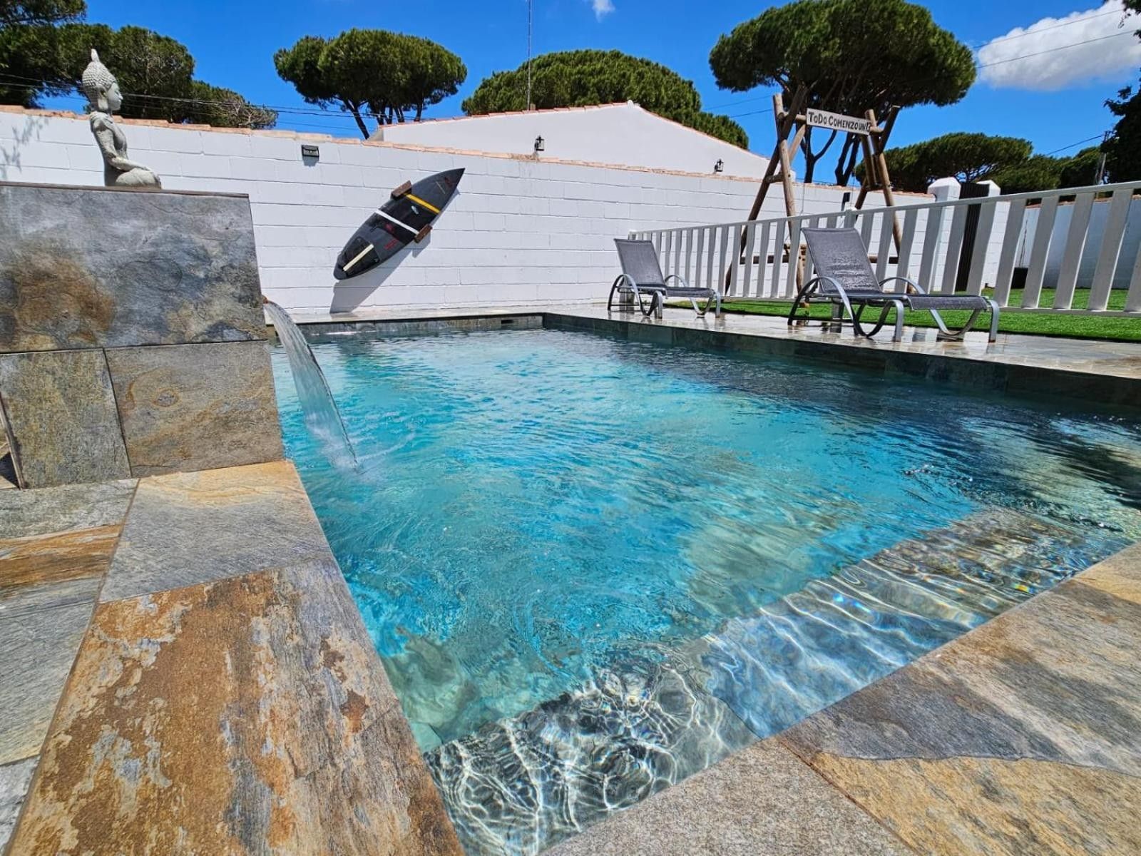 Una piscina con acqua cristallina, un trampolino e una statua.