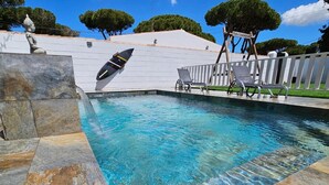 Piscina com água cristalina, prancha de mergulho e uma estátua.