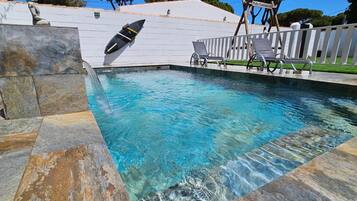 Una piscina con acqua cristallina, un trampolino e una statua.