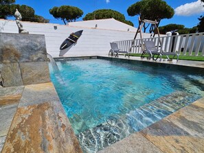 Una piscina con acqua cristallina, un trampolino e una statua.