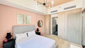 A bedroom with a bed, nightstands, a mirror, and a wardrobe. - Premium Holiday Apartment at La Perla  (Dubai)