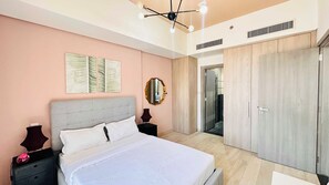 A bedroom with a bed, nightstands, a mirror, and a wardrobe. - Premium Holiday Apartment at La Perla  (Dubai)