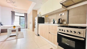 A modern kitchen with a built-in oven, a stove, and a microwave. There is a small dining table with a plant on it. - Premium Holiday Apartment at La Perla  (Dubai)