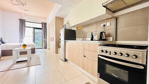 A modern kitchen with a built-in oven, a stove, and a microwave. There is a small dining table with a plant on it. - Premium Holiday Apartment at La Perla  (Dubai)