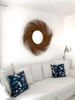 Un sofá blanco con almohadones florales y un adorno redondo en la pared.