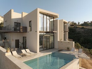 A modern two-story building with a rooftop pool, outdoor seating, and a view of the surrounding landscape. - Sapera Villa I, Iconic Architecture & Sea Views (Rethymno)
