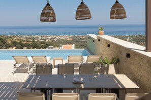 Terraza en la azotea con piscina, mobiliario y vistas a la costa.