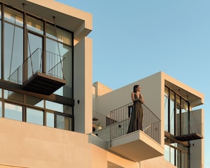 Un edificio moderno con varios balcones, ventanas amplias y cielo despejado.