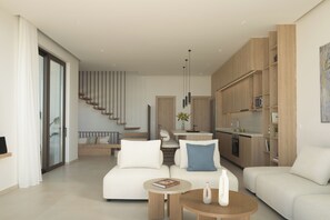 Ein modernes Wohnzimmer mit Sofa, Couchtisch und Essbereich, im Hintergrund eine Küche.