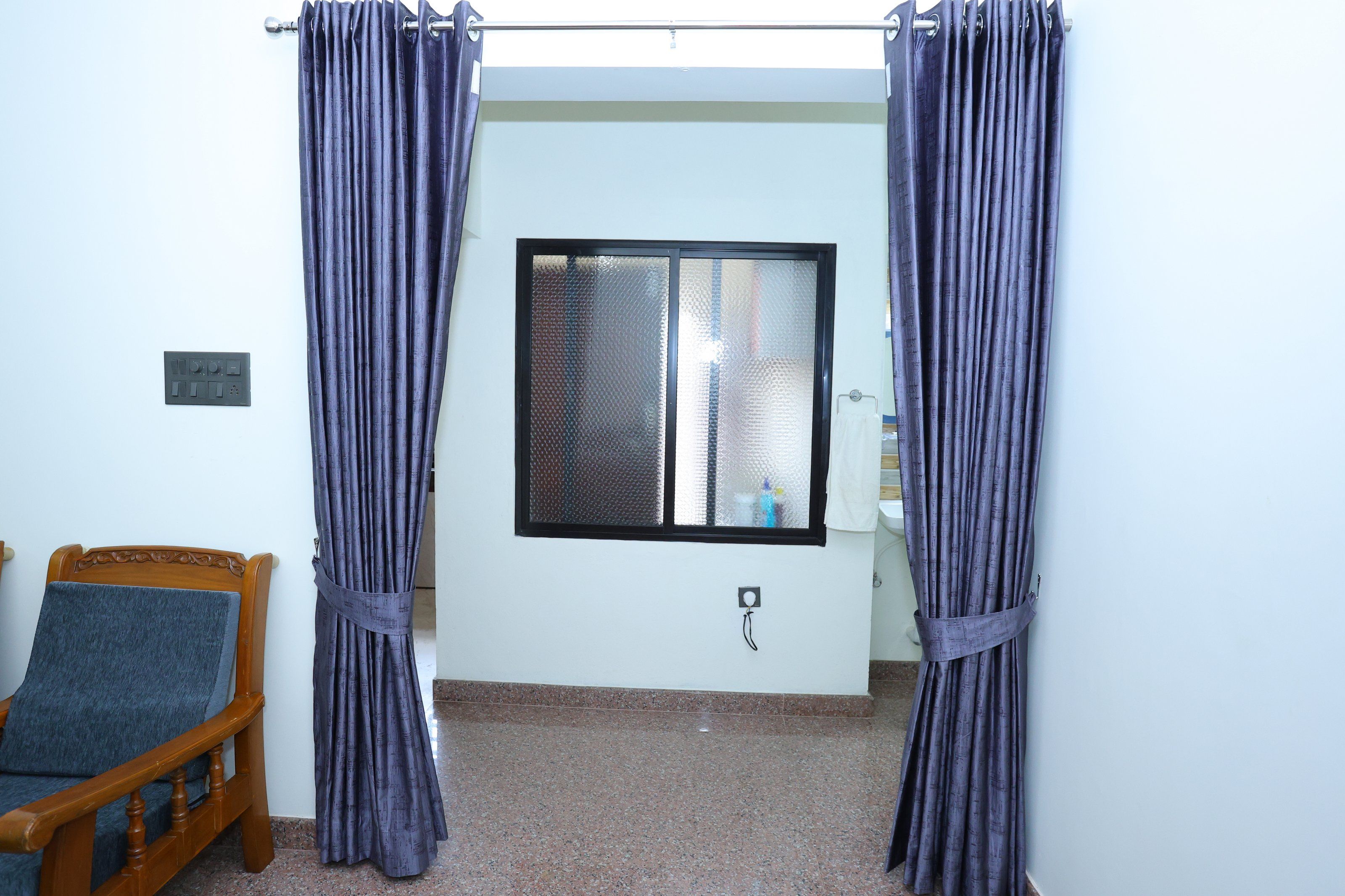 Una habitación con una cama, un ventanal con panel de vidrio esmerilado y una barra para cortinas.