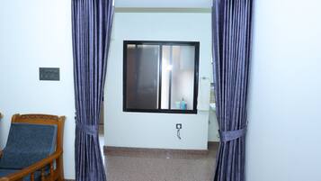 Una habitación con una cama, un ventanal con panel de vidrio esmerilado y una barra para cortinas.