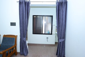 Una habitación con una cama, un ventanal con panel de vidrio esmerilado y una barra para cortinas.