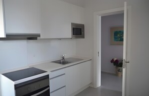 Eine moderne Küche mit weißen Schränken, einer Edelstahl-Spüle und einer Mikrowelle.