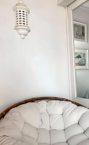 Ein Zimmer mit einer weißen Wand, einer gepolsterten Sitzgelegenheit in Weiß und einer weißen Wandleuchte.
