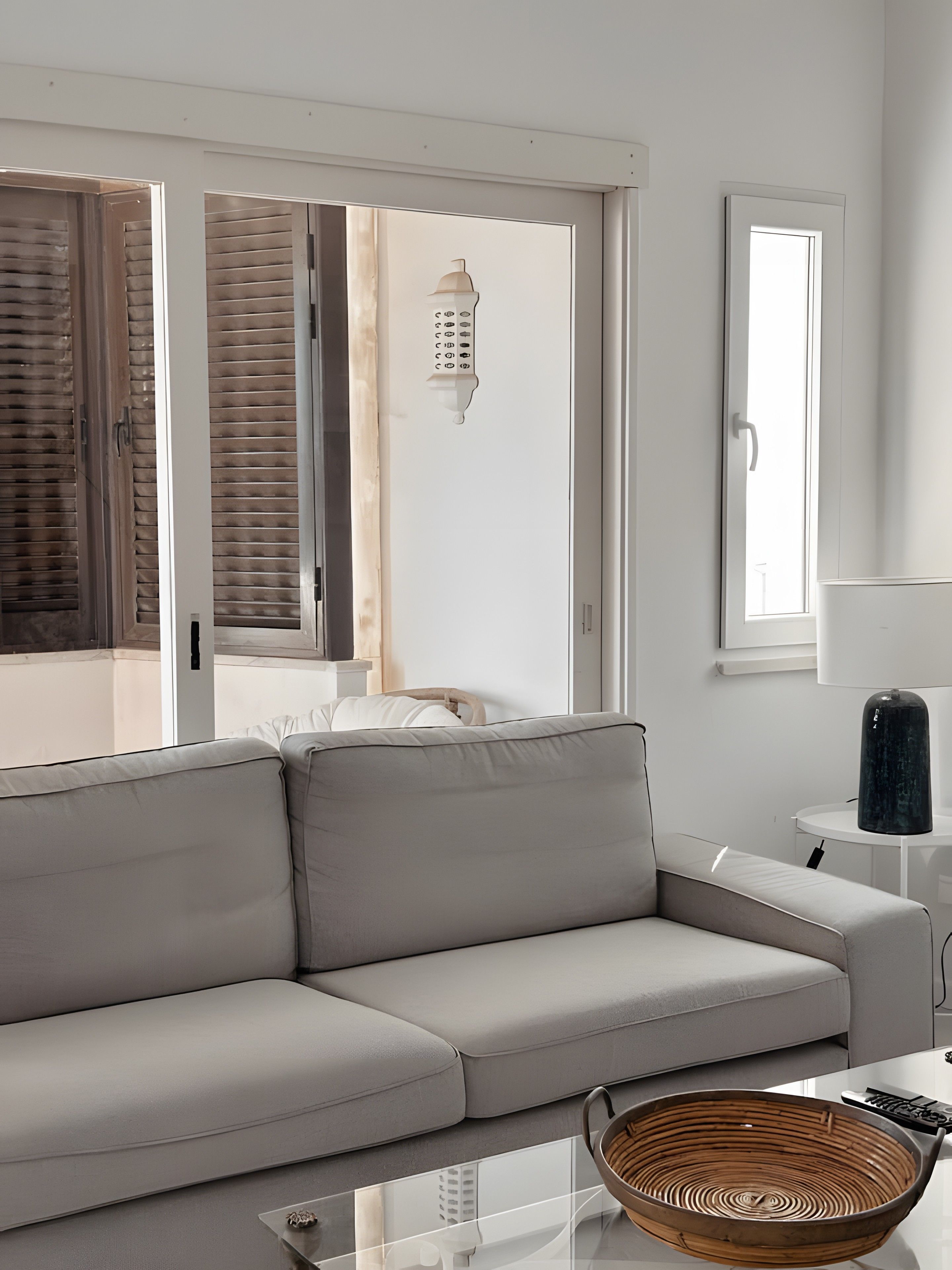 Un soggiorno moderno con un divano grigio, un tavolino in vetro e un cesto di vimini.
