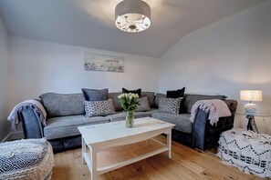 A living room with a grey sofa, a white coffee table, and a lamp on a side table. - Norfolk Coast Beach House - Family & Dog Friendly - 4 Bed - Award Winning Luxury (Heacham)