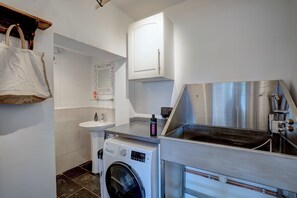 A compact laundry area with a washing machine, a sink, and a stainless steel sink with a hose. - Norfolk Coast Beach House - Family & Dog Friendly - 4 Bed - Award Winning Luxury (Heacham)