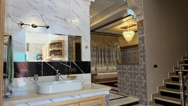 Een moderne badkamer met een marmeren wastafelmeubel, een grote spiegel en een kroonluchter.