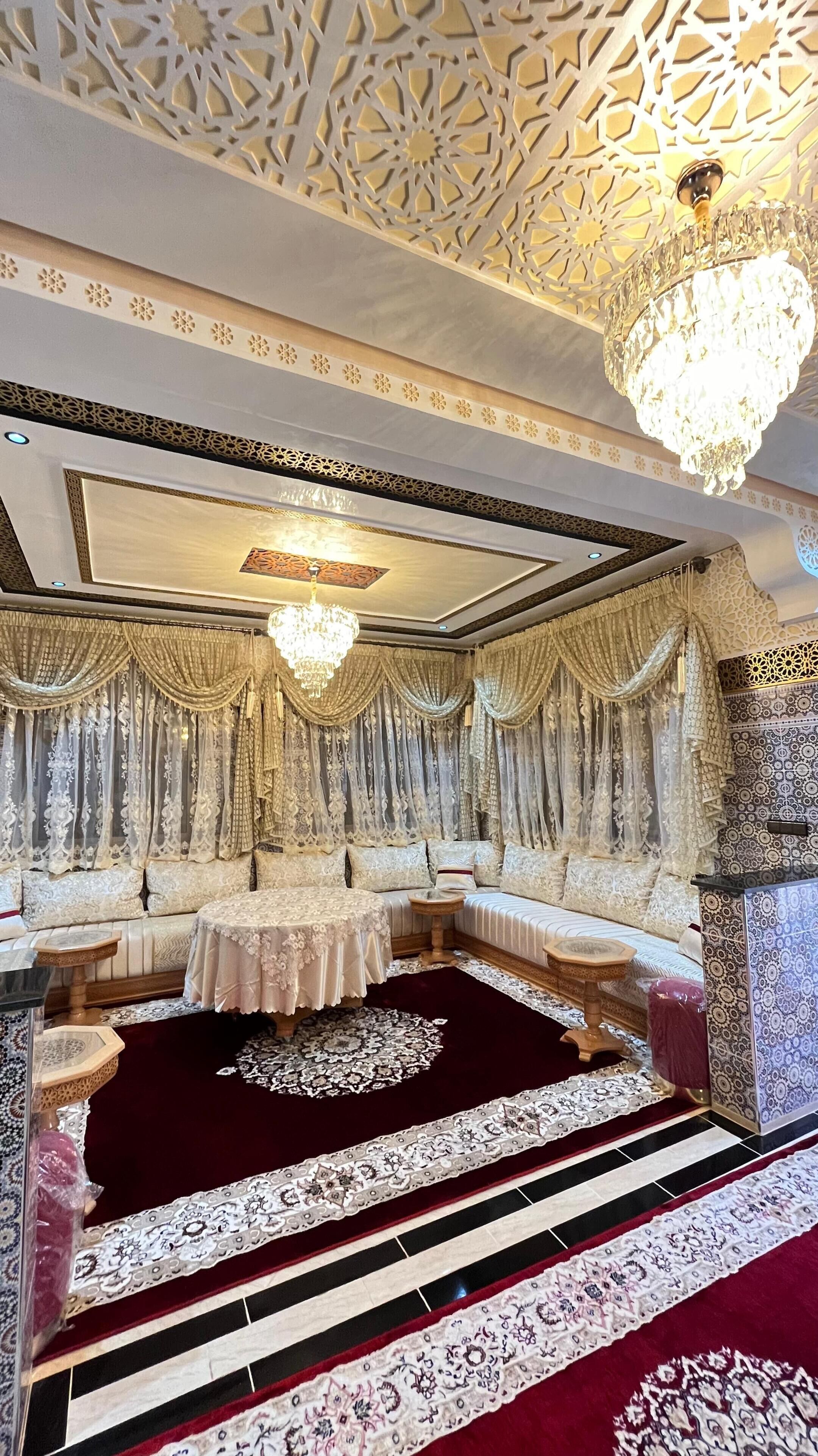 Una habitación lujosa con intrincados diseños en el techo, un candelabro y una zona de estar cómoda.