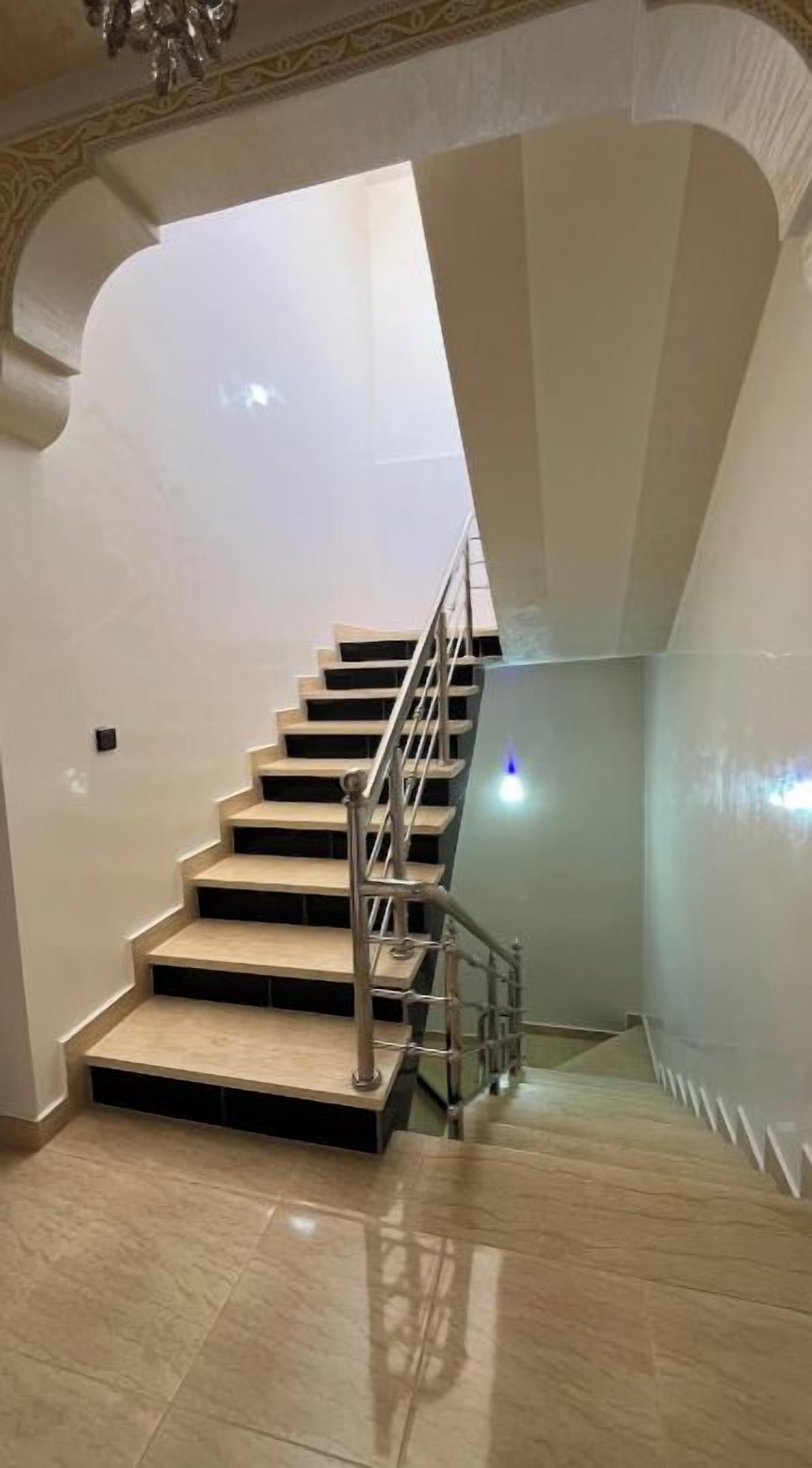 Una escalera con barandilla de metal que lleva a un piso superior.