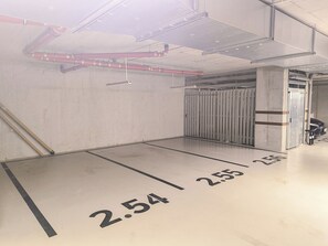 Eine Parkgarage mit Betonwänden, Metallbarrieren und einem freien Boden mit Parkplatznummern.