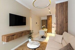 A modern living room with a flat-screen TV, a wooden bench, a dining area with a table and chairs, and a sofa. - Chmielna Duo Royal | Warsaw Center & Parking (Warszawa)