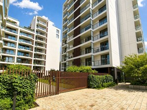 Ett modernt bostadskomplex med flera våningar, balkonger och en grind vid ingången.