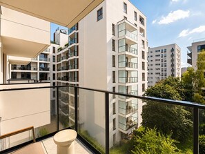 Ein modernes Apartmenthaus mit mehreren Balkonen, großen Fenstern und Blick auf die umliegende Grünfläche.