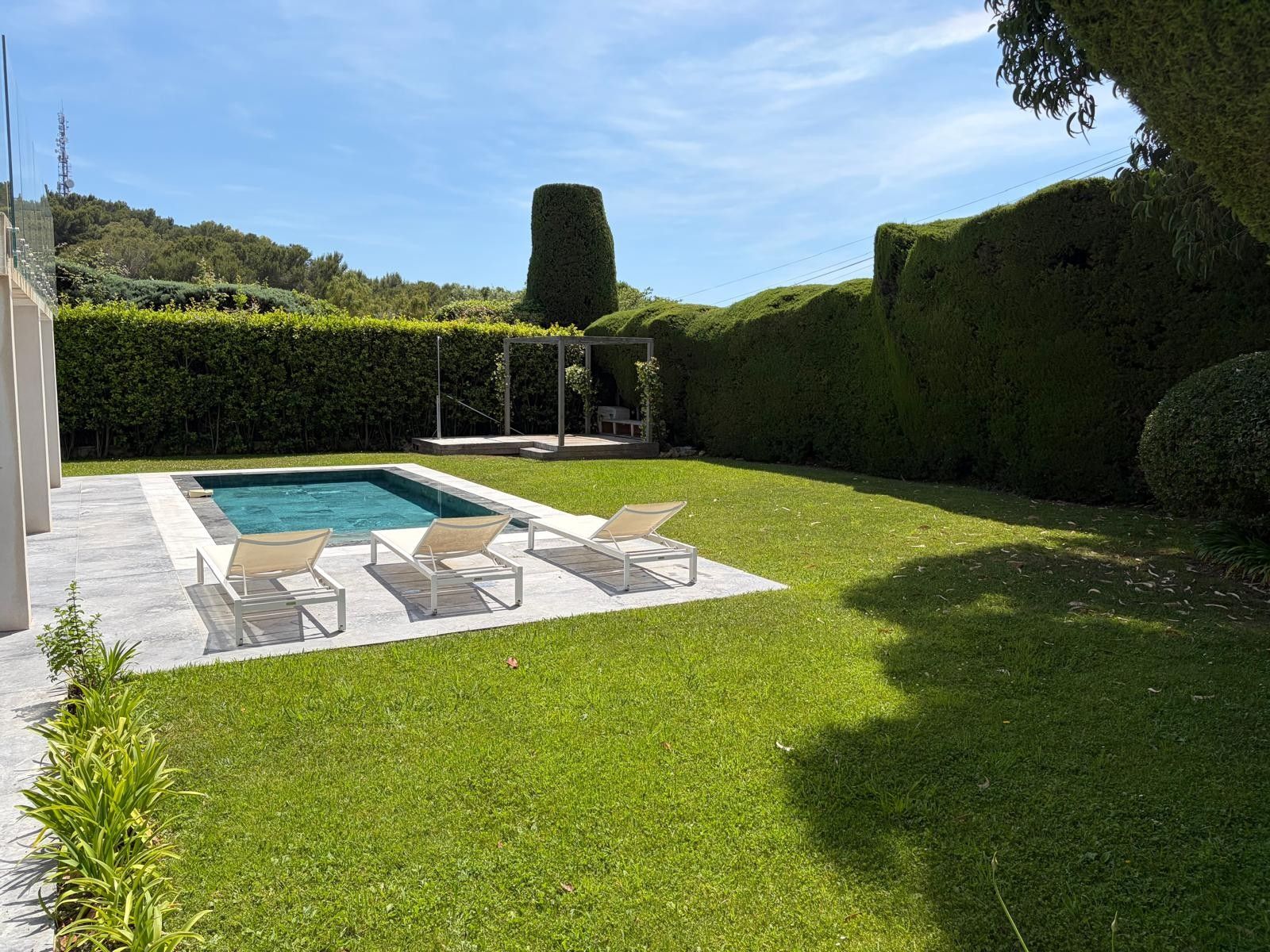 A backyard with a swimming pool, lounge chairs, and a pergola.