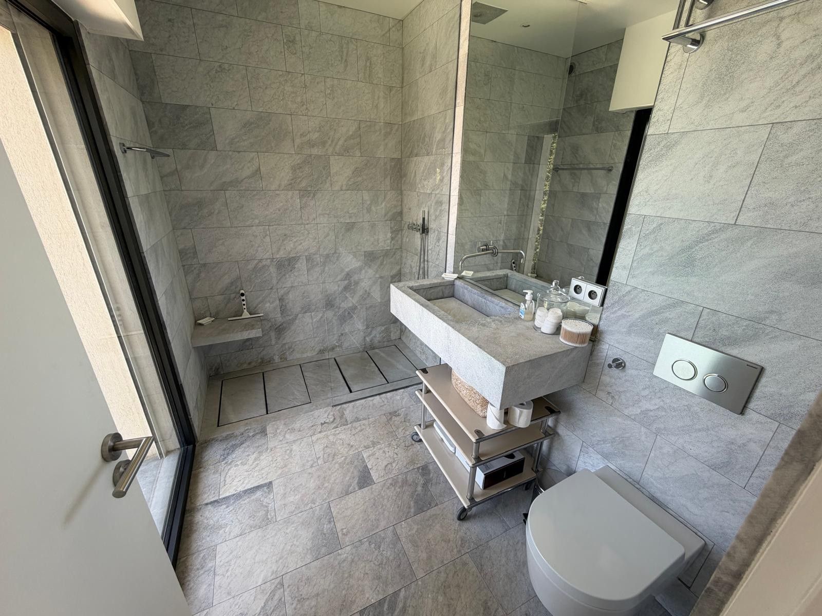 A modern bathroom with a large sink, mirror, and shower area.