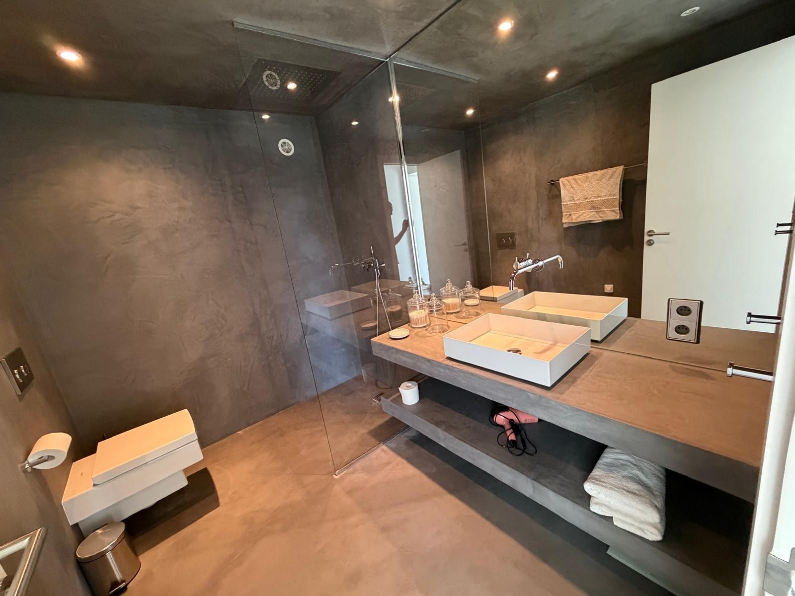 Un bagno moderno con uno specchio grande, due lavabi e una zona doccia.