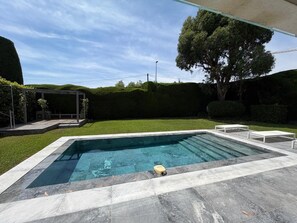 A rectangular swimming pool with a tiled deck, surrounded by a well-maintained lawn and a pergola structure. - Villa "Julia" with Sea View, Wi-Fi, and Air Conditioning (Vallauris)