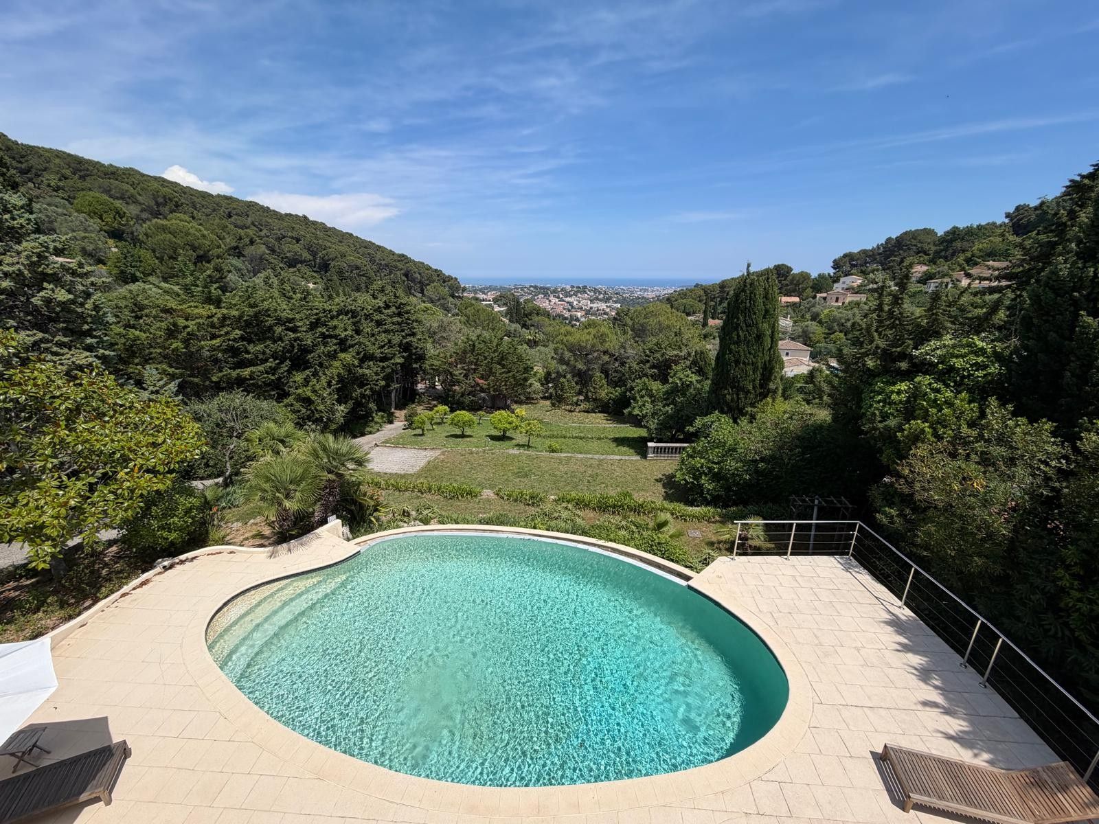 A swimming pool with a curved edge, surrounded by a paved deck.