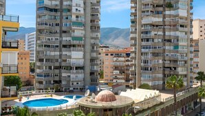 Un palazzo residenziale di grandi dimensioni con numerosi balconi, una piscina e vista su una montagna.