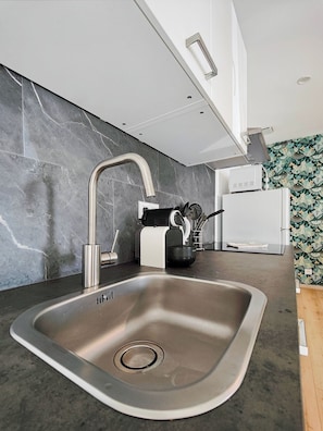 Una cocina moderna con un lavamanos de acero inoxidable, extractor de aire empotrado y microondas.