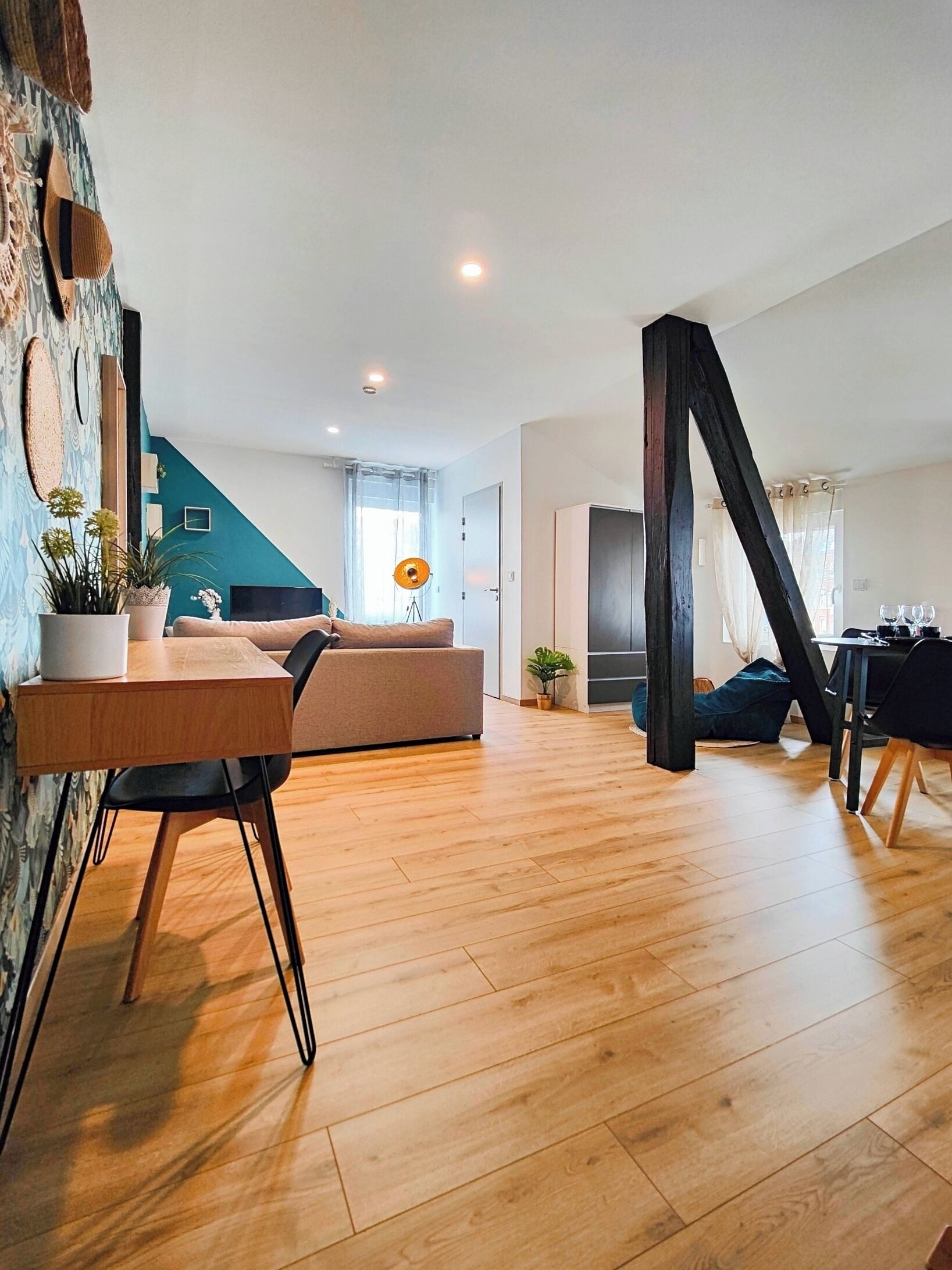 A modern living room with a wooden floor, a sofa, a dining table, and a staircase.