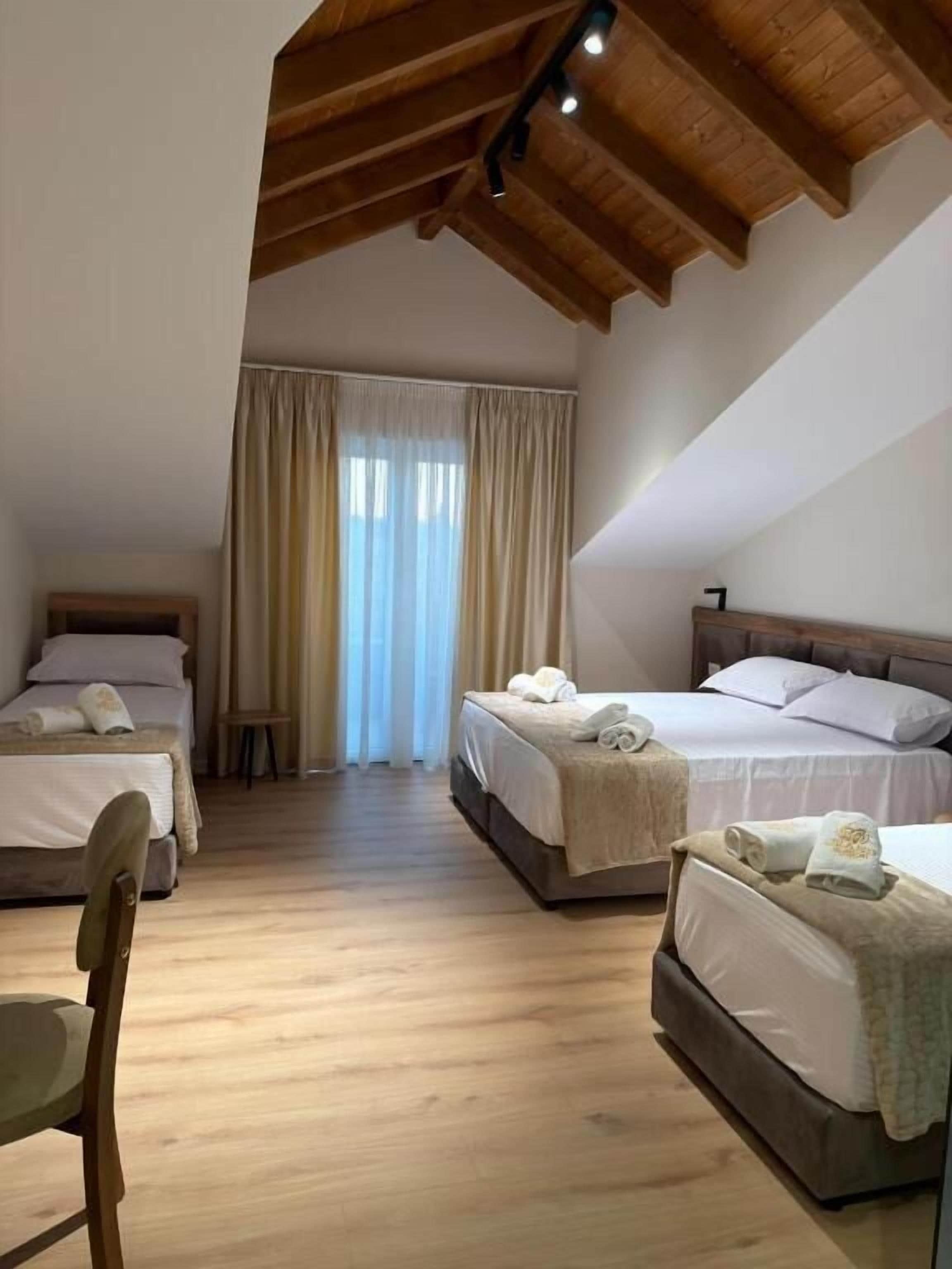 A bedroom with two beds, wooden flooring, and a sloped ceiling.