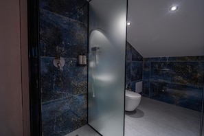 A modern bathroom with a glass partition, a white toilet, and a marble wall. - Grand Station Hotel  (Shkodër)
