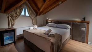 Een slaapkamer met een houten plafond, een bed met hoofdeinde, een nachtkastje en een kleine koelkast.