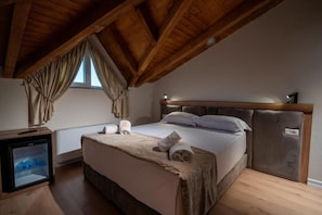 A bedroom with a wooden ceiling, a bed with a headboard, a bedside table, and a small refrigerator. - Grand Station Hotel  (Shkodër)