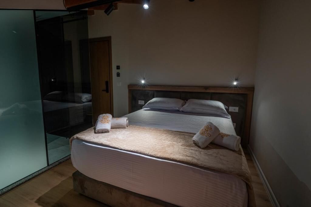 Un dormitorio con una cama grande, un separador de vidrio y un cabecero de madera.