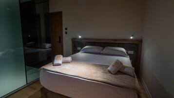 Un dormitorio con una cama grande, un separador de vidrio y un cabecero de madera.