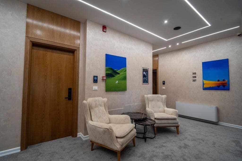 A hotel lobby with two armchairs, a small table, and artwork on the walls.