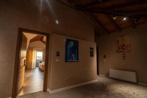 A hotel corridor with a wooden ceiling, a door leading to a room, and artwork on the walls.