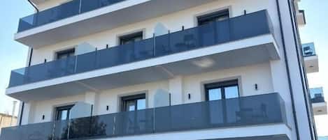 Un hotel de varios pisos con un llamativo letrero 'GRAND STATION', balcones en cada planta y un piso principal con diseño decorativo.