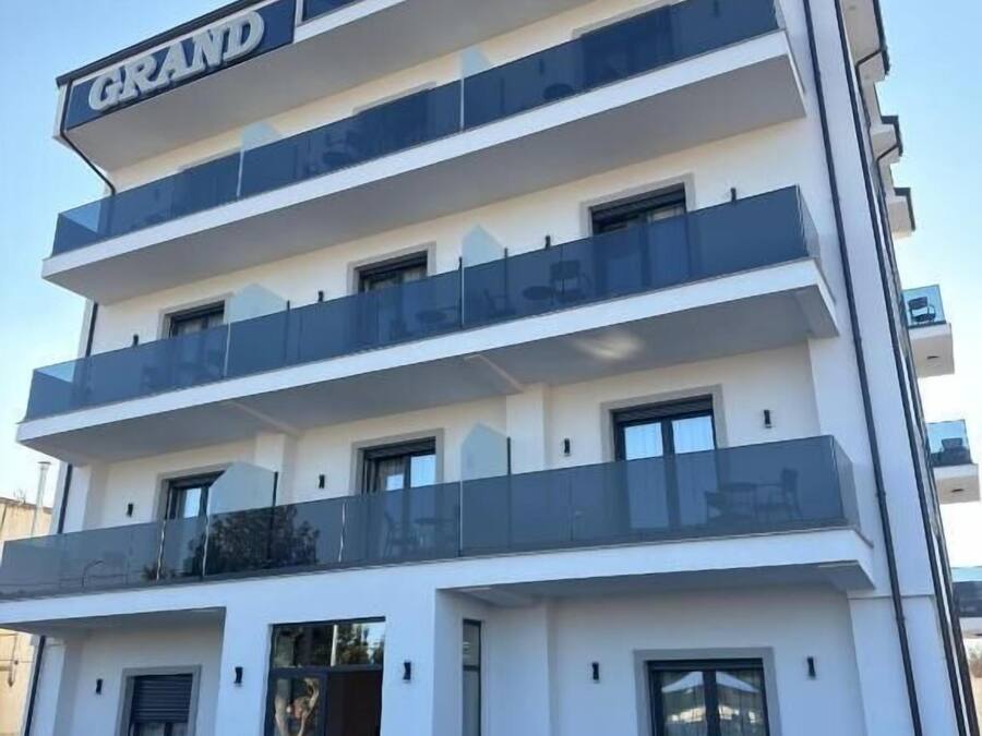 Un hotel de varios pisos con un llamativo letrero 'GRAND STATION', balcones en cada planta y un piso principal con diseño decorativo.