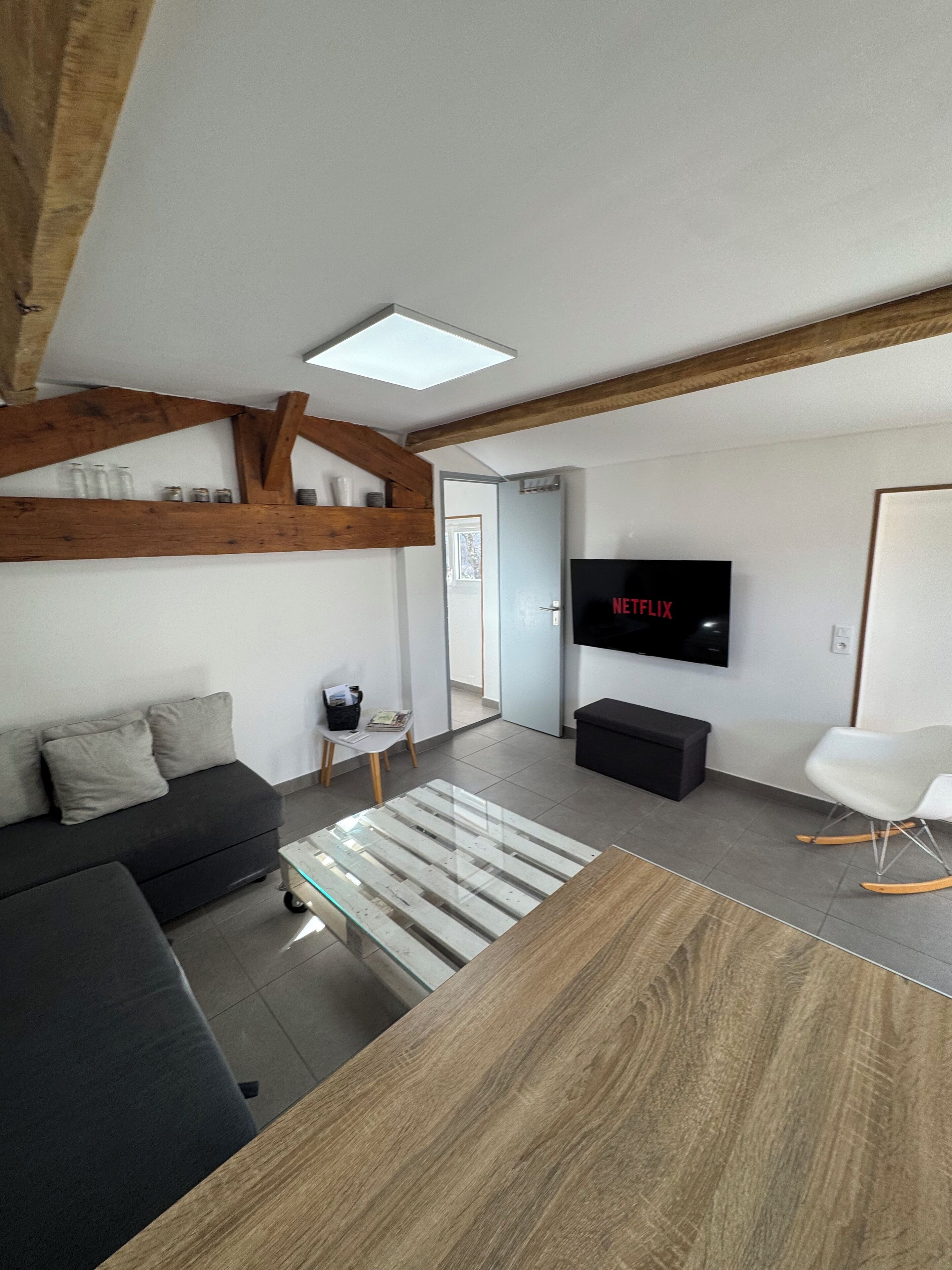 Una sala moderna con un sofá, una mesa de centro, un televisor y una viga de techo de madera.