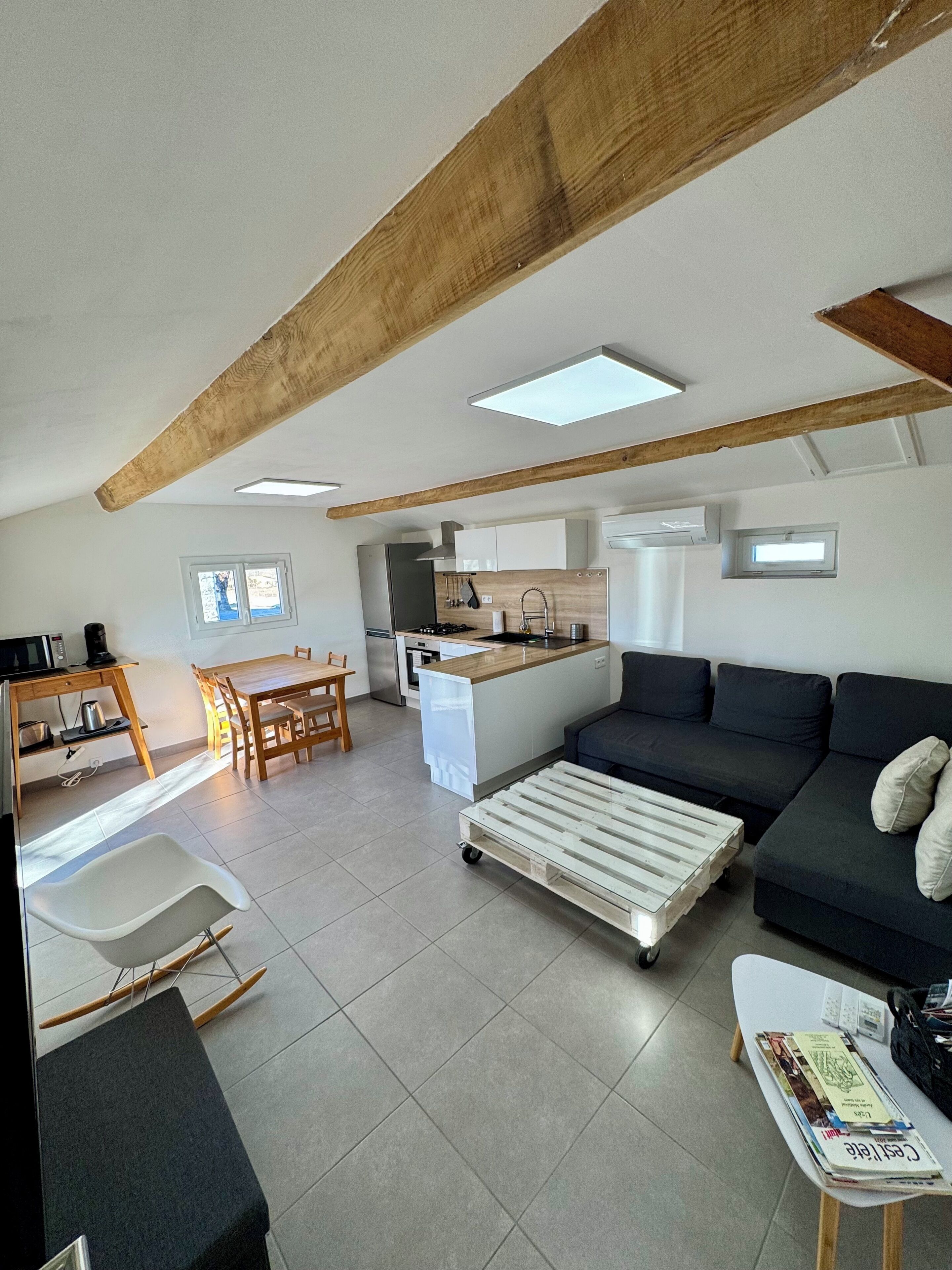 Un espai de vida modern amb zona de menjador, cuina americana i zona d'estar.