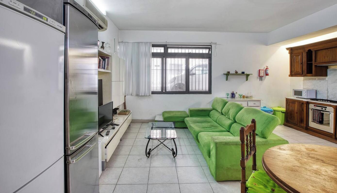 Un soggiorno con un divano verde, una TV e un tavolo da pranzo.